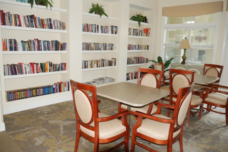 A cozy library reading area with bookshelves, a table, and chairs.