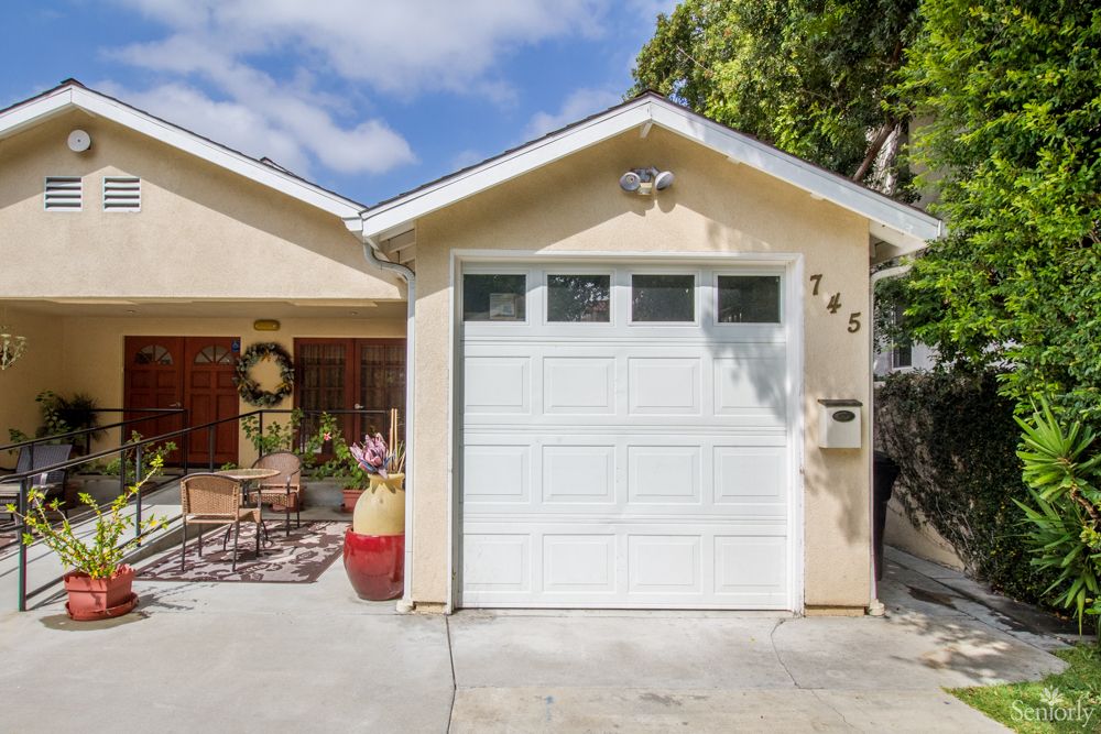 A cozy residential home with a single-car garage and a small front porch decorated with outdoor furniture.