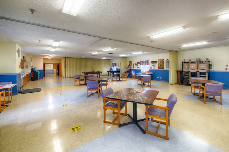 A spacious community area with multiple tables and chairs arranged for social or group activities.