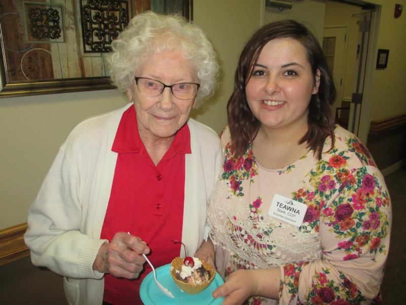 An elderly woman and a young woman smiling together while celebrating with cake.