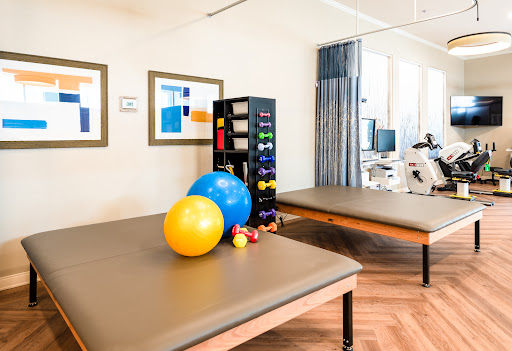 A well-equipped therapy room featuring exercise balls, weights, and comfortable treatment surfaces.