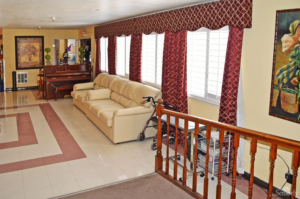 A cozy living room with a beige sofa, elegant red curtains, and a decorative mirror.