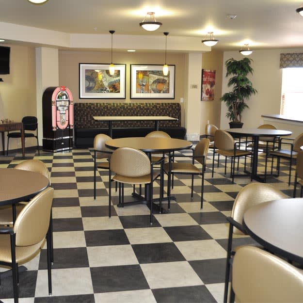 An empty cafe with checkered flooring, round tables, and a jukebox.