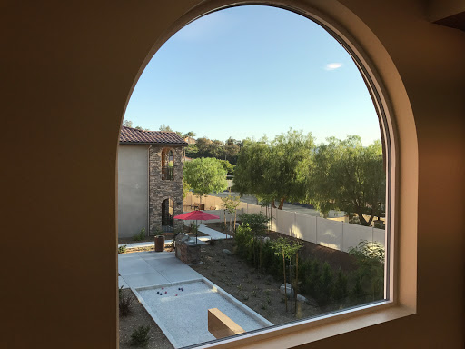 A picturesque view from an arched window, showcasing greenery and a serene outdoor space.