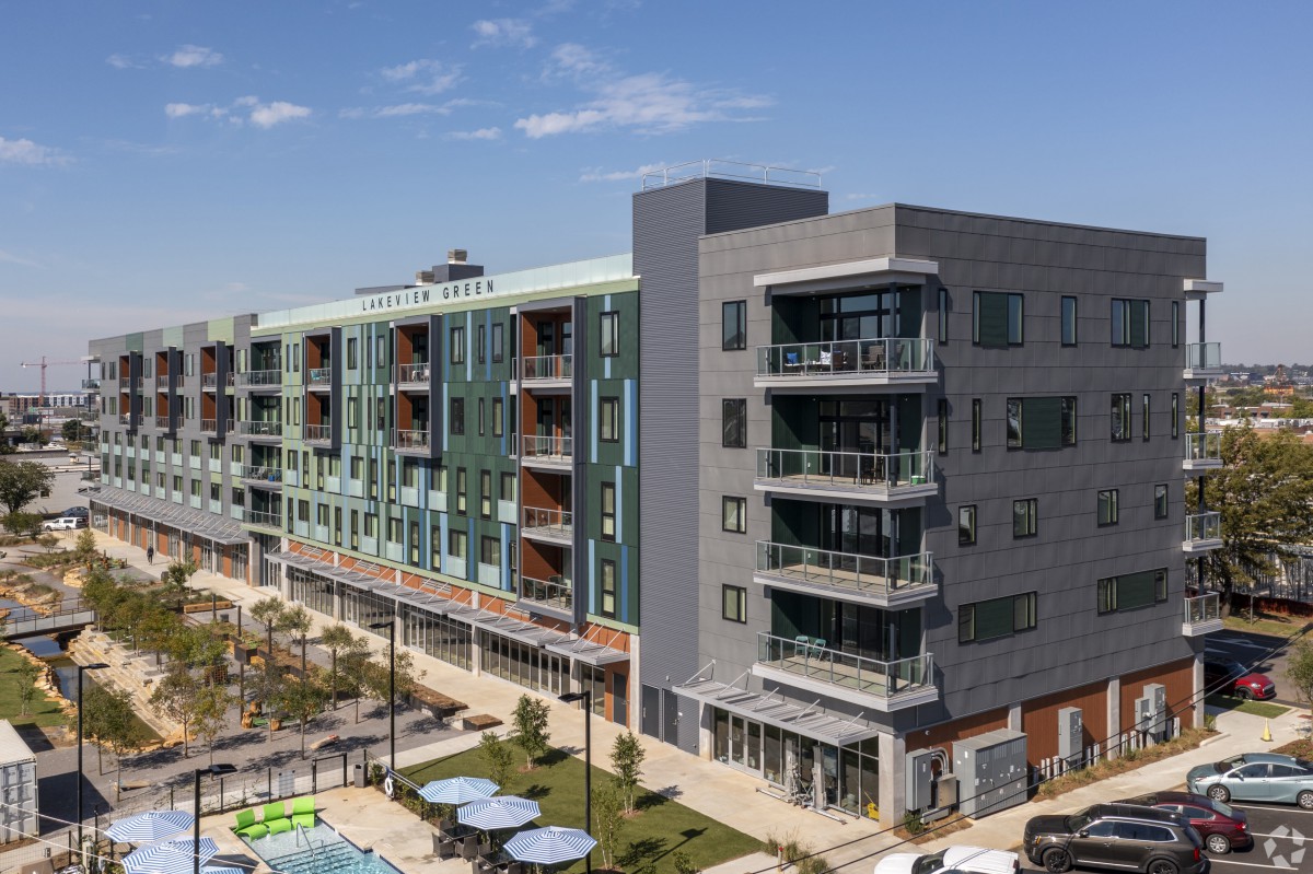 A modern multi-story apartment building with balconies and a landscaped outdoor area.