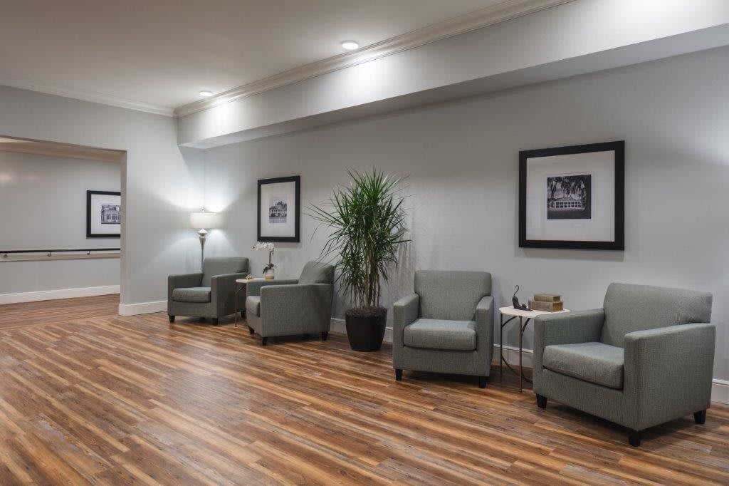 A modern waiting room with comfortable chairs, a potted plant, and framed artwork on the walls.