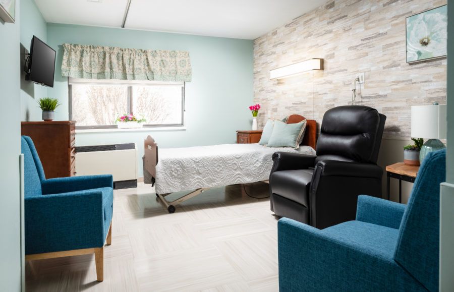 A modern and comfortable hospital room with a single bed, recliner chair, and bright decor.
