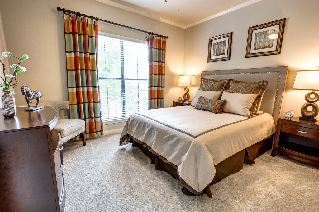 A cozy and well-decorated bedroom featuring a neatly made bed, colorful curtains, and warm lighting.