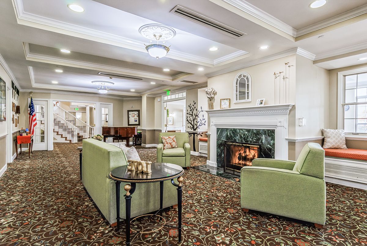 A cozy living room with a fireplace, green armchairs, and elegant decor.