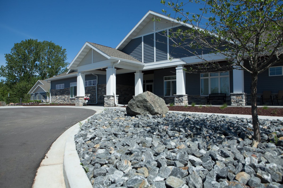 A modern building with a rock landscape in the foreground under a clear blue sky.