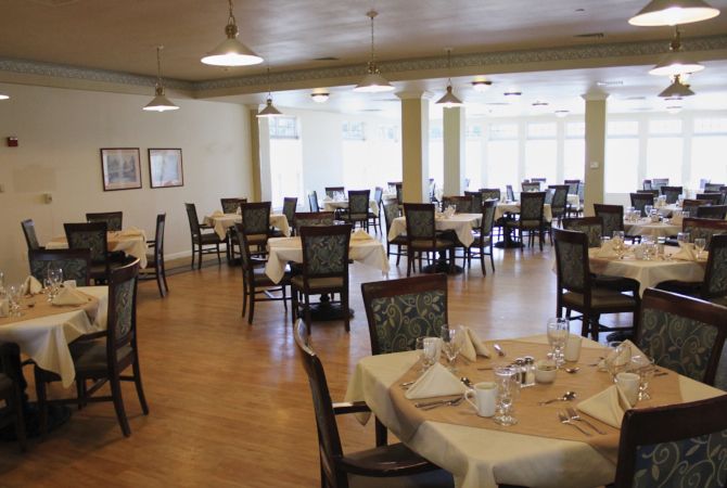 An empty dining room with neatly set tables and chairs arranged in a spacious layout.