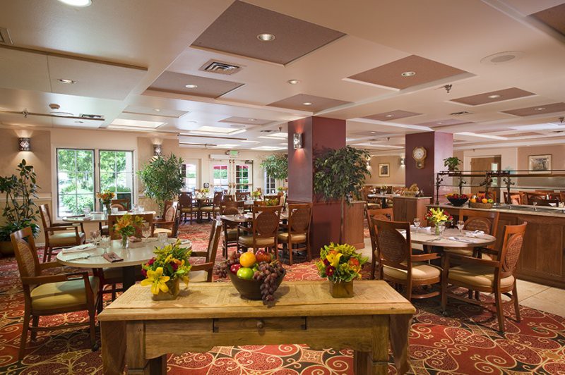 A cozy restaurant interior with neatly arranged tables and chairs, decorated with plants and flowers.