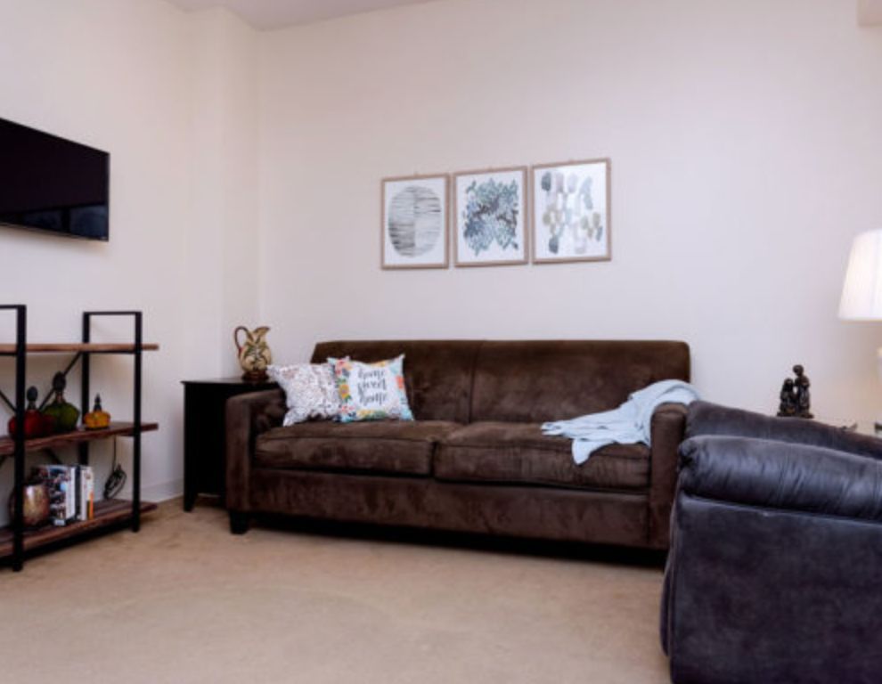 A cozy living room featuring a brown sofa, decorative cushions, and wall art.