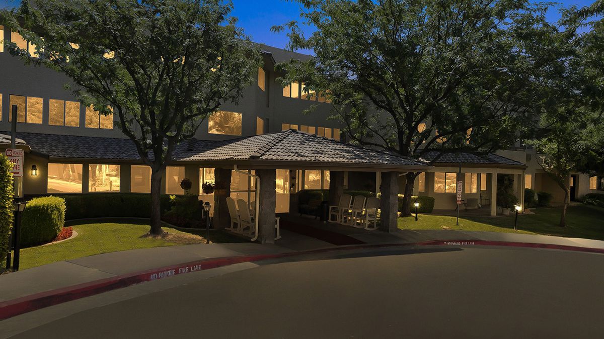 A well-lit building entrance at night with surrounding trees.