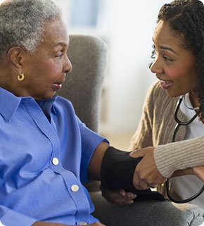 A healthcare professional checks the blood pressure of an elderly patient.