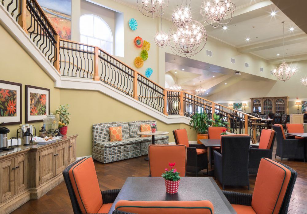 A spacious and inviting lobby with elegant chandeliers, comfortable seating, and a decorative staircase.