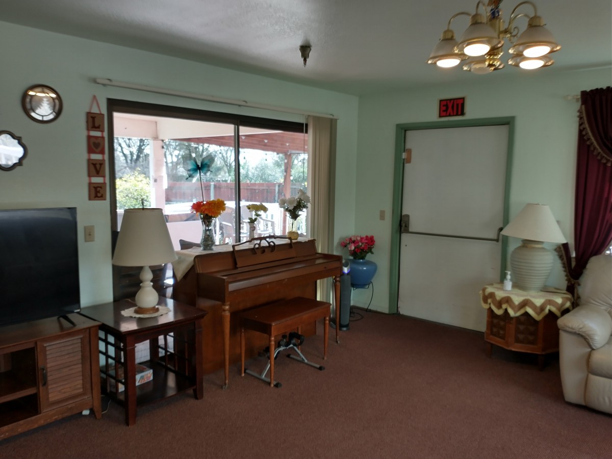 A cozy room with a piano, lamps, and a window overlooking the outdoors.