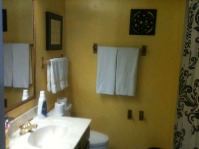 A bathroom with towels hanging on the wall and a sink with toiletries.