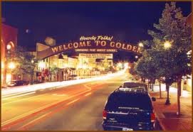 A night view of the 'Welcome to Golden' sign over a brightly lit street.