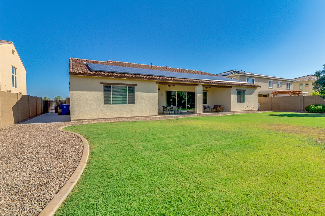 A sunny day showcasing a house with solar panels and a well-maintained lawn.