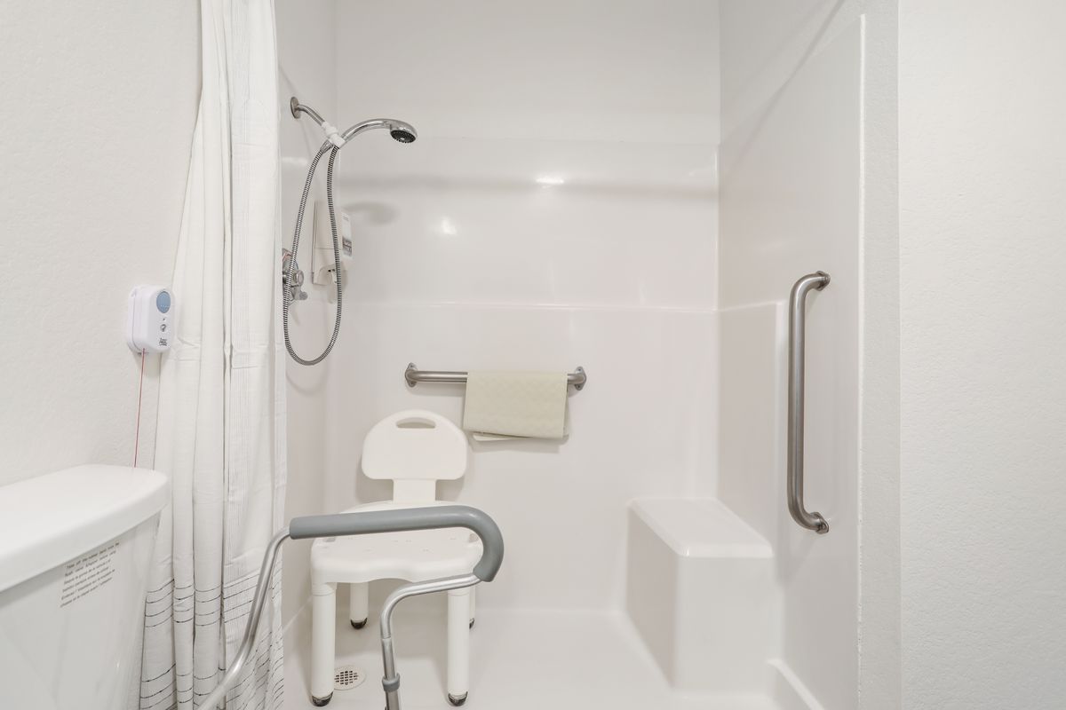 An accessible shower equipped with a shower chair and grab bars.