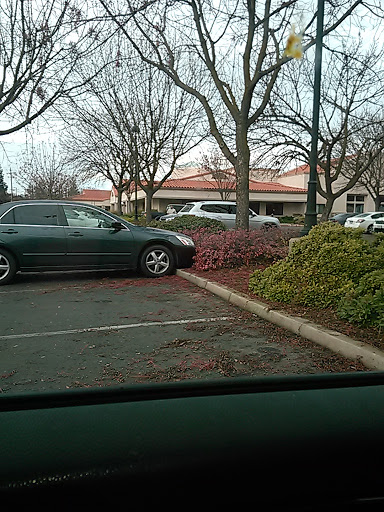 A car parked improperly on the edge of a parking lot, encroaching on the sidewalk.