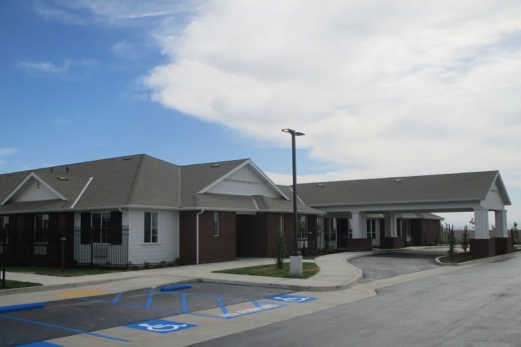 A view of a single-story building with a parking lot and clear blue sky.