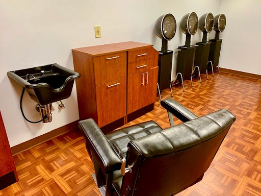 A hair salon interior featuring a styling chair, hair dryers, and a sink.