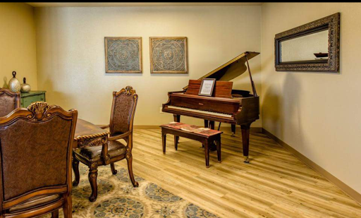 A cozy interior featuring a grand piano and elegant wooden dining set, complemented by decorative art pieces on the wall.