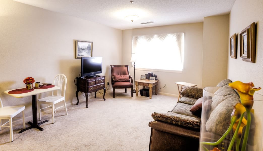 A cozy living room with a television, chairs, and a sofa.
