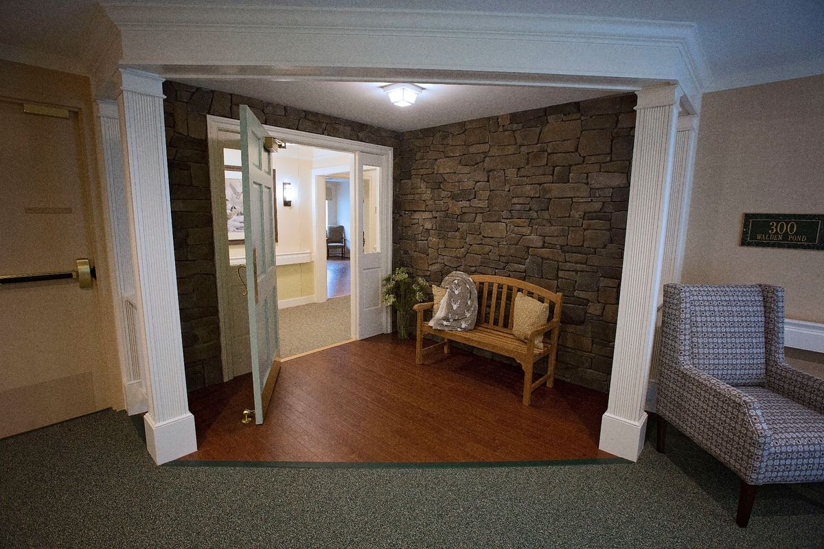 A cozy interior space featuring a stone wall, wooden bench, and potted plant by an open doorway.