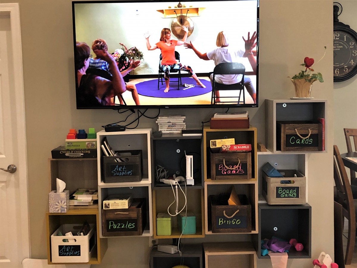 A living room setup with a TV mounted on the wall above organized storage shelves.