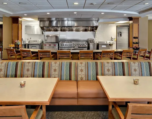 A view of a modern restaurant's dining area, featuring comfortable seating and an open kitchen.