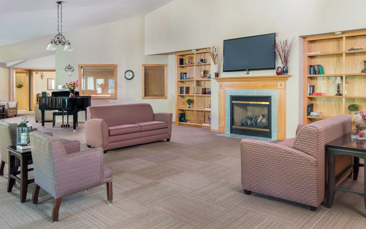 A cozy living room featuring modern furniture, a television above the fireplace, and a piano.