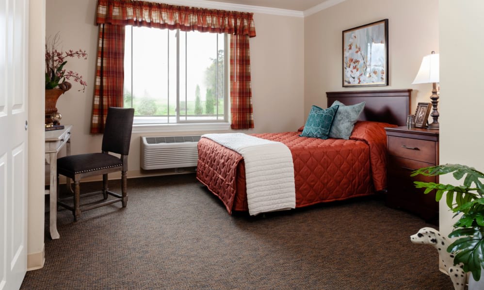 A cozy hotel room with a neatly made bed, a window allowing natural light, and elegant decor.