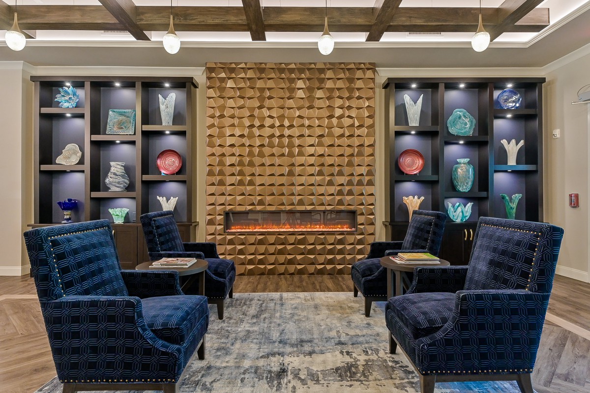 A modern lounge with blue chairs, a stylish fireplace, and decorative shelves.