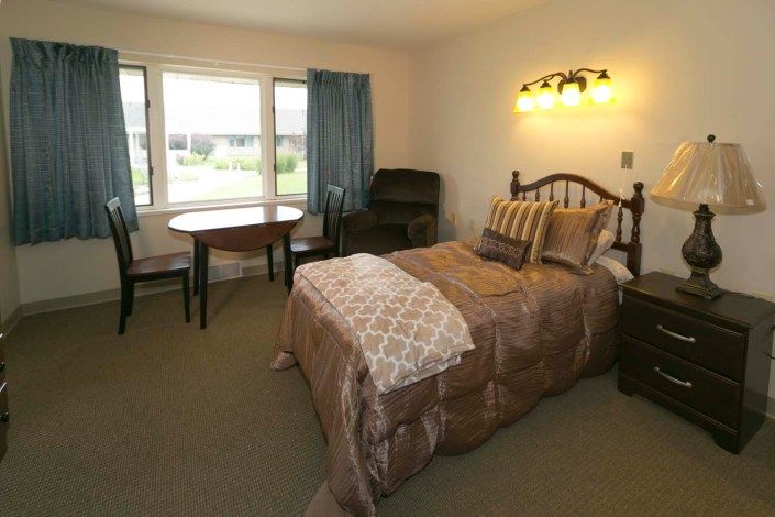 A cozy bedroom with a single bed, a table, and a chair near the window.