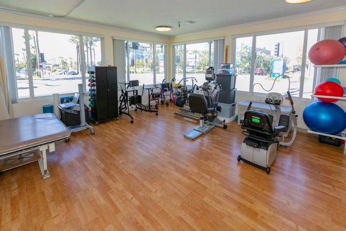 A well-equipped gym with various exercise machines on a wooden floor.