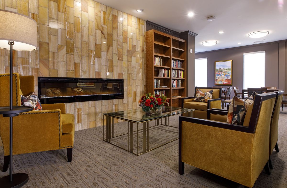 A cozy living room with a modern design, featuring a fireplace, bookshelf, and comfortable seating.