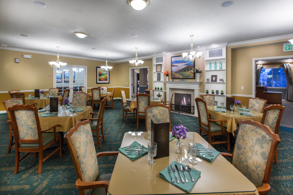 An elegant dining room featuring neatly set tables, comfortable chairs, and a cozy fireplace.
