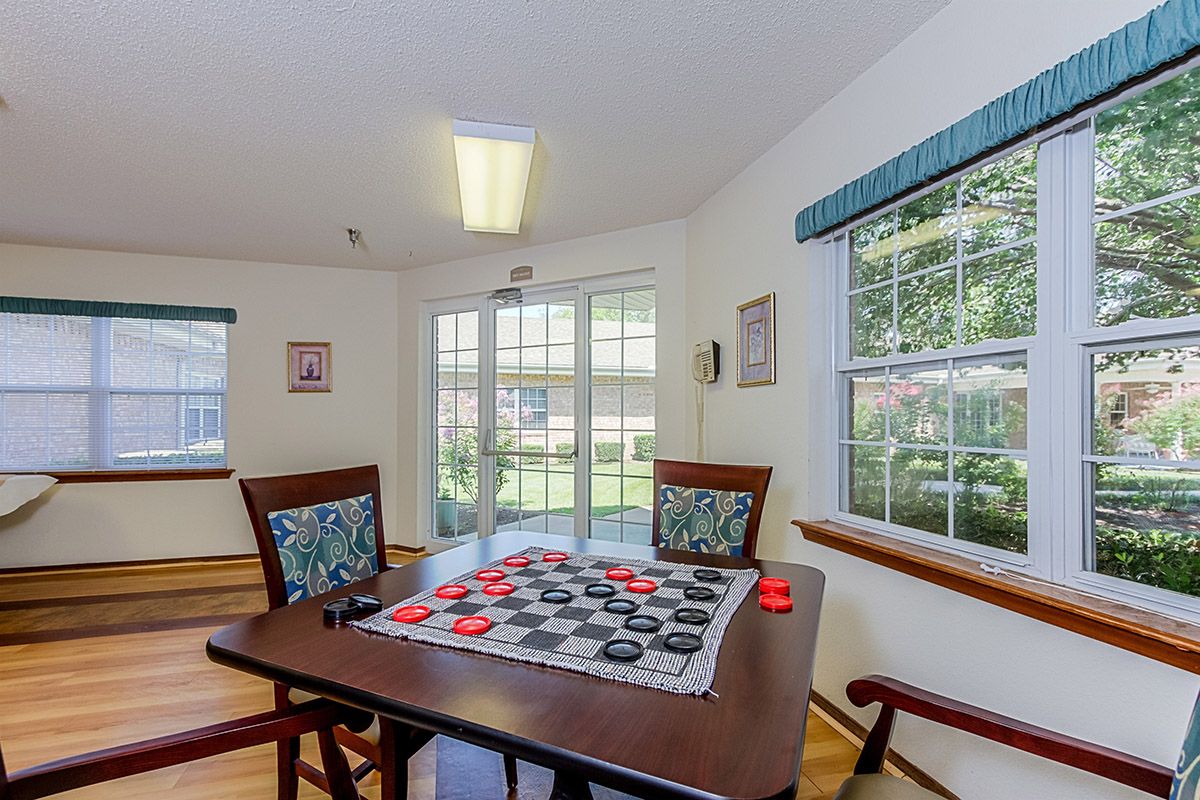 A cozy game room with a checkers board set up on a table near large windows.