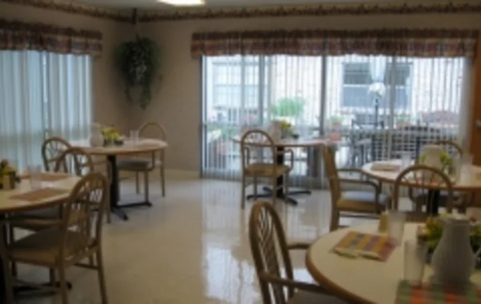 A cozy dining area with tables and chairs by large windows.
