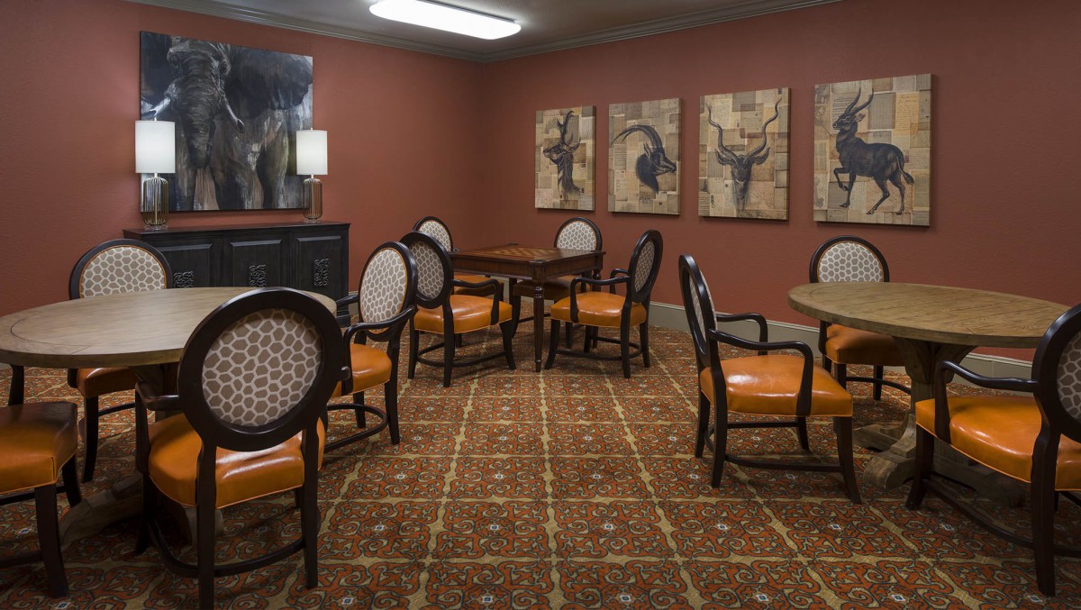 A cozy room with several tables and chairs, adorned with wall artwork and a patterned carpet.