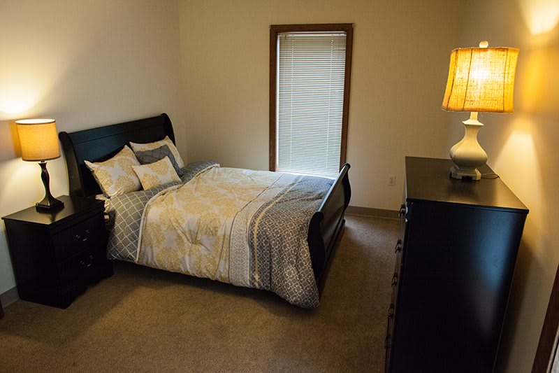 A cozy bedroom with a bed, side lamp, and window.