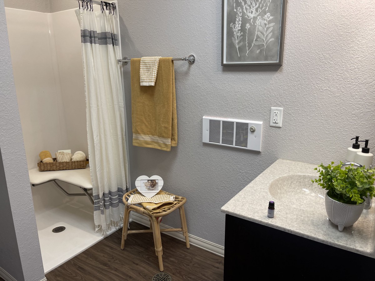 A neatly organized bathroom featuring a sink, shower, and decorative elements like towels and a stool.