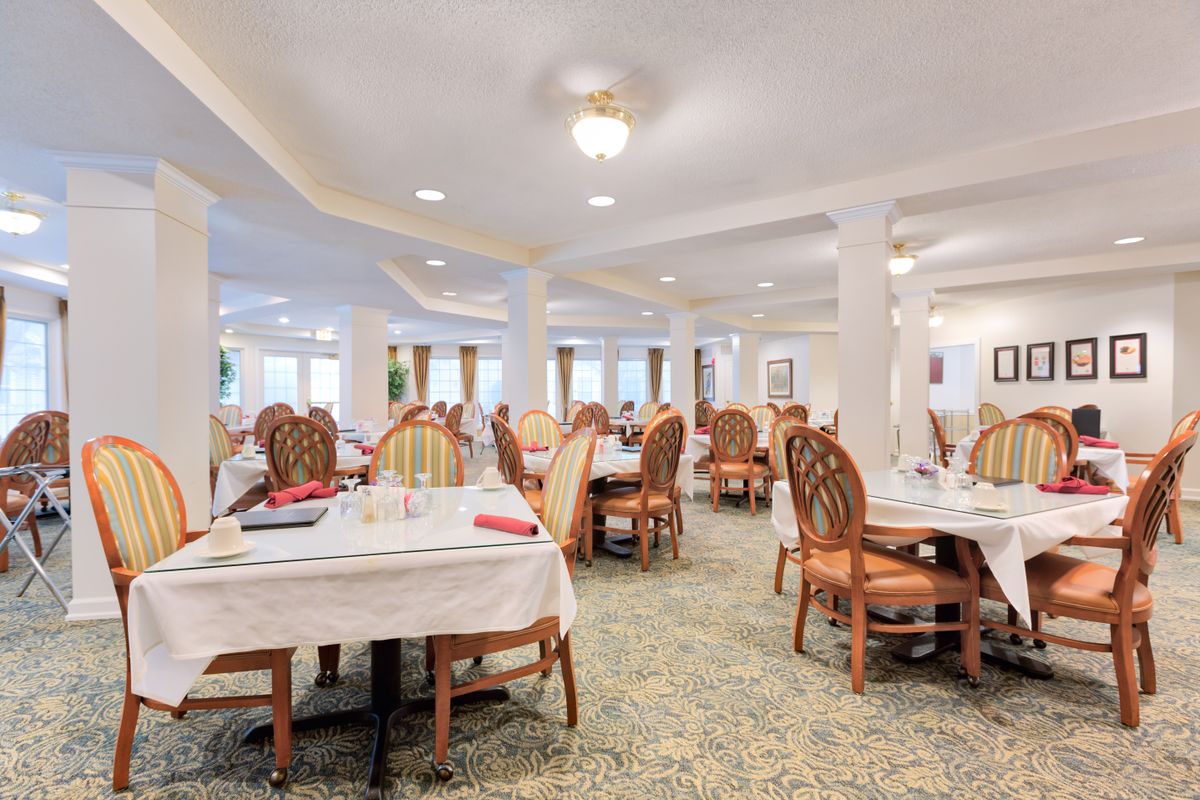 A spacious dining room with elegantly set tables and comfortable seating.
