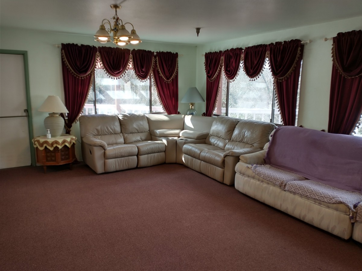 A cozy living room with sofas, red curtains, a chandelier, and a carpet.