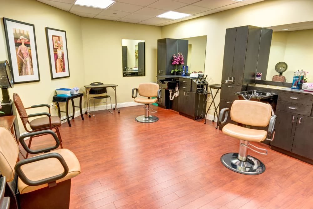 A modern hair salon with stylish chairs and mirrors, featuring a wooden floor and sleek interior design.