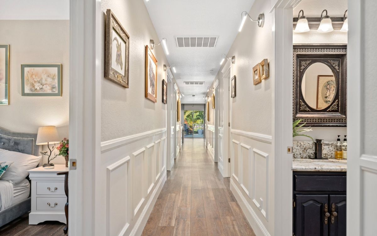 A beautifully decorated hallway with framed artwork and elegant wainscoting.