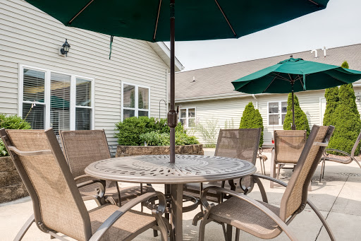A cozy patio setting featuring a round table surrounded by comfortable chairs and umbrellas for shade.